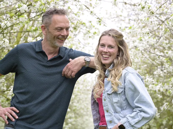 Shelley Kil en Bram de Wever, de makers van Nomade, lachend tussen bloesembomen